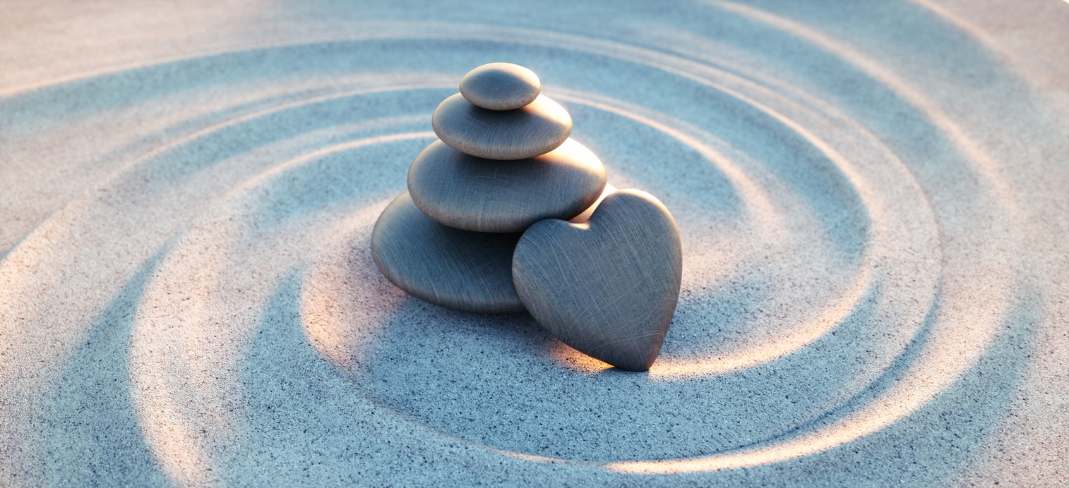 Stack of pebbles with heart shaped pebble and spiral sand waves