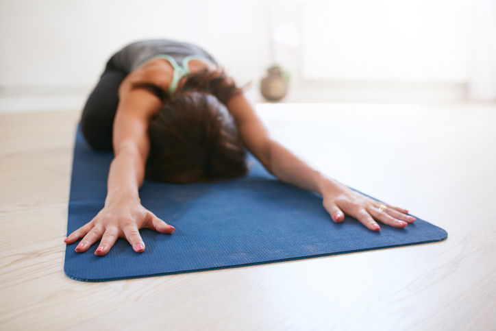 Woman doing stretching workout on fitness mat. Fit female performing yoga on exercise mat at gym. Child Pose, Balasana.