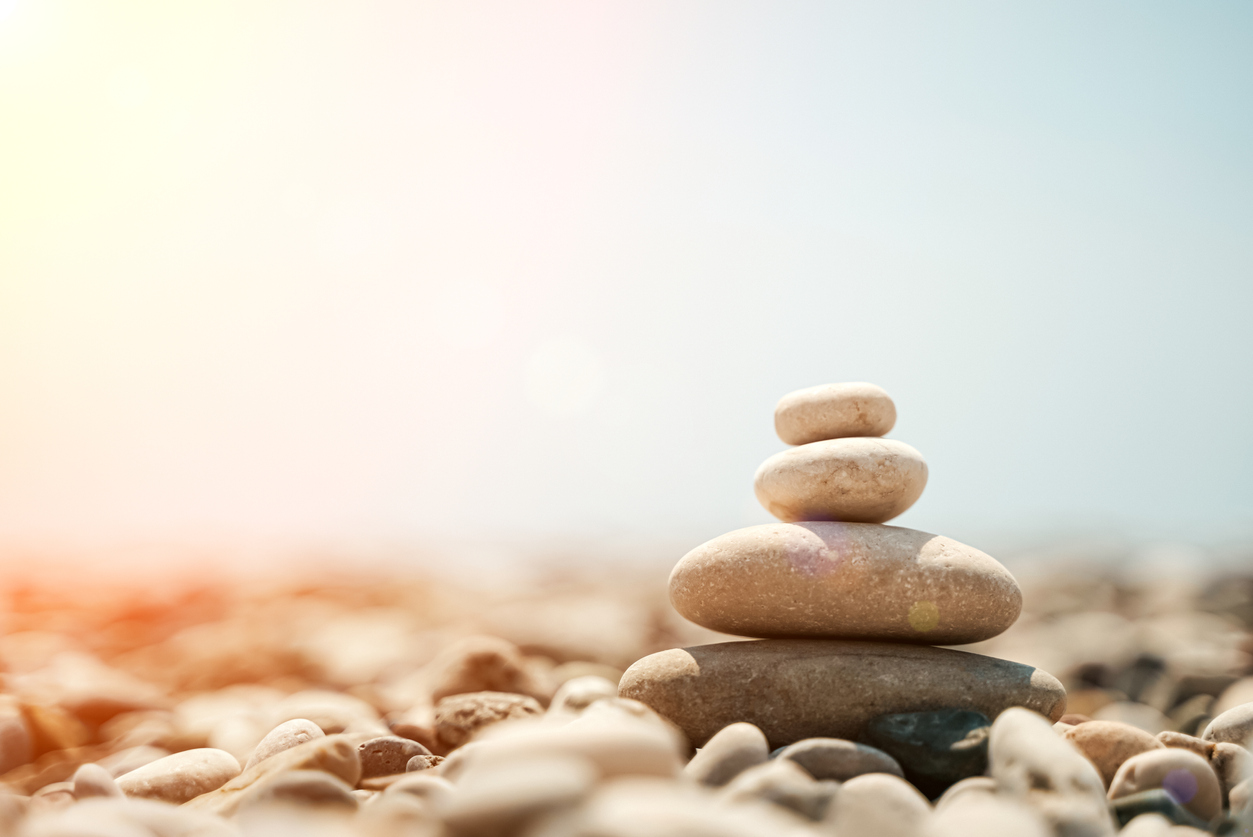 Zen stones are background. A pyramid of pebble stones against the background of the sky, sea and beach. Meditation, yoga, calming the mind and relaxation concept. High quality photo