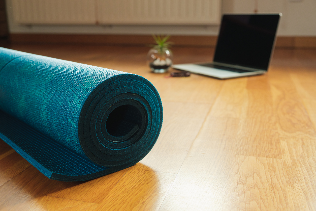 Yoga mat and laptop prepared for an online yoga class at home. Selective focus, background.