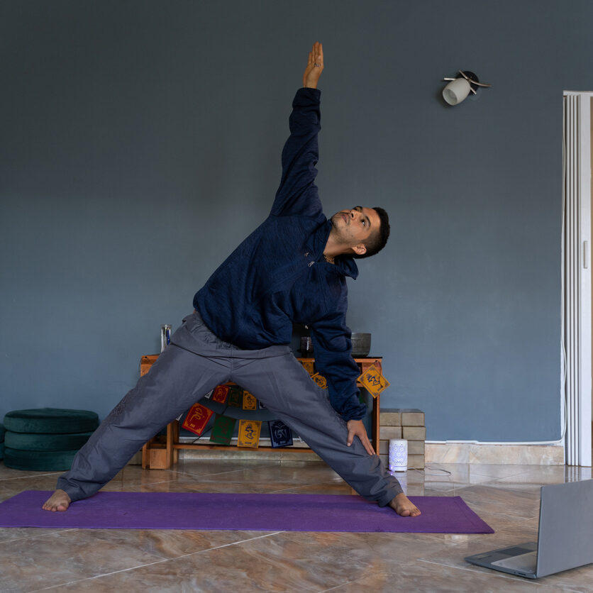 Young latin man practices virtual yoga in the comfort of his home